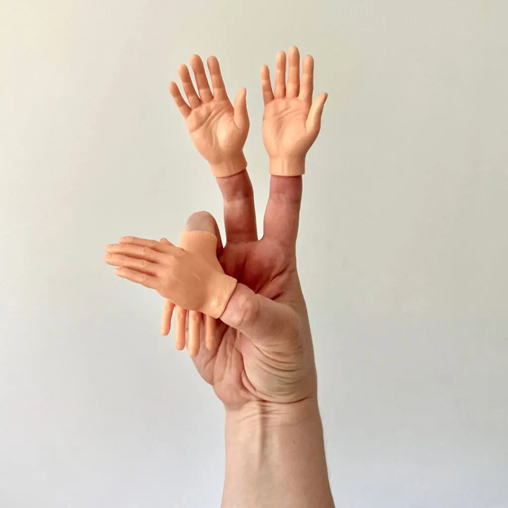 Someone's hand wearing finger puppets that look like little hands