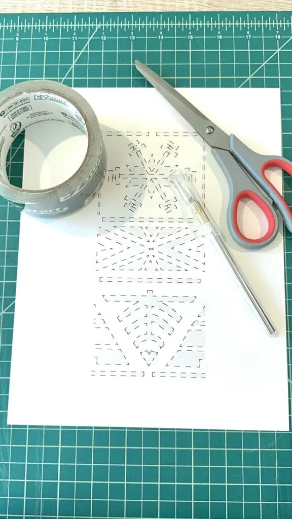 a stencil pattern printed on a piece of paper. Scissors and an exacto knife lie next to the paper