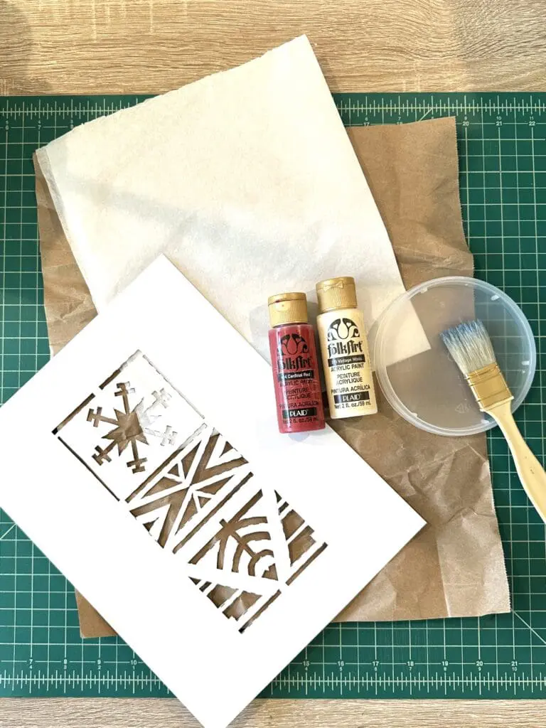 Paper, paint, and a stencil on a cutting mat