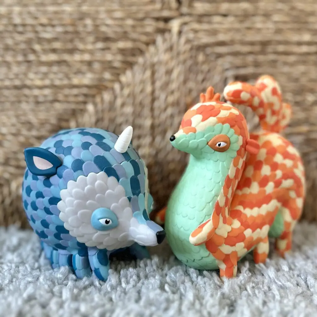 Two strange-looking vinyl toy creatures, one blue, one orange
