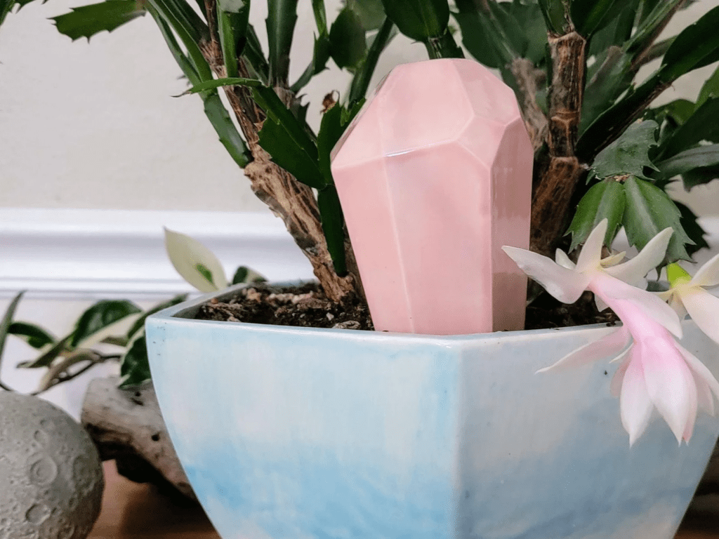 Watering stake shaped like a pink crystal, in a plant pot